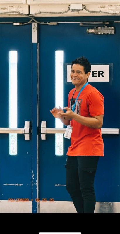 A greeter in an orange Renewal shirt smiling at the front doors